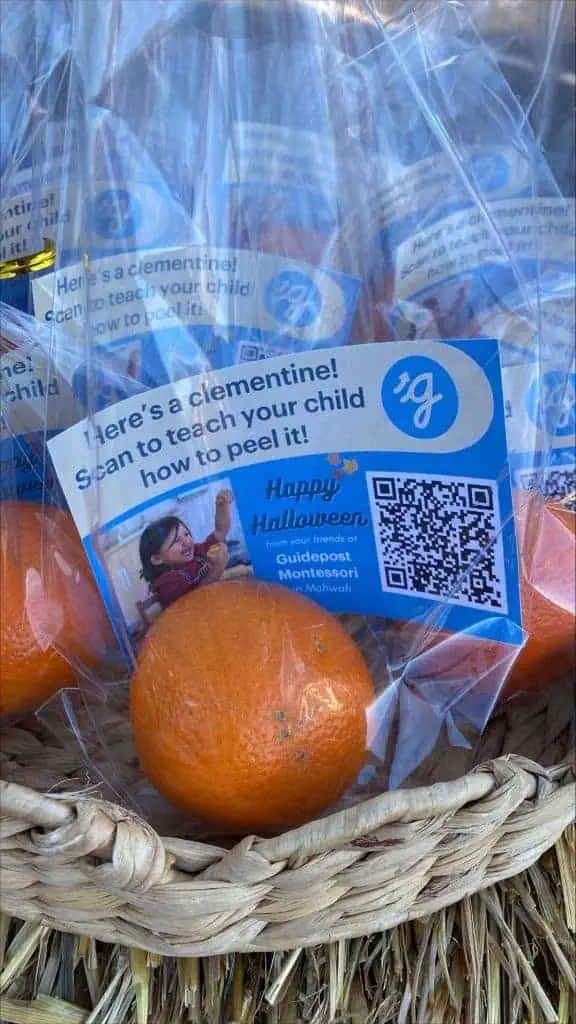 Bagged clementines with a Guidepost Montessori label inviting parents to scan a QR code to watch a Montessori lesson on peeling a clementine.