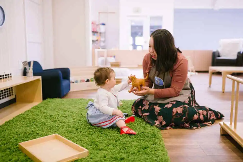 Montessori guide observing and engaging with an infant during floor-based learning