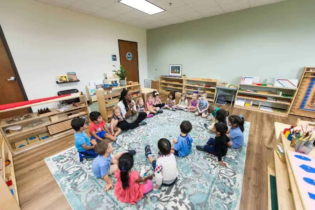 Guidepost Montessori teacher sitting in circle with diverse group of young children during morning meeting
