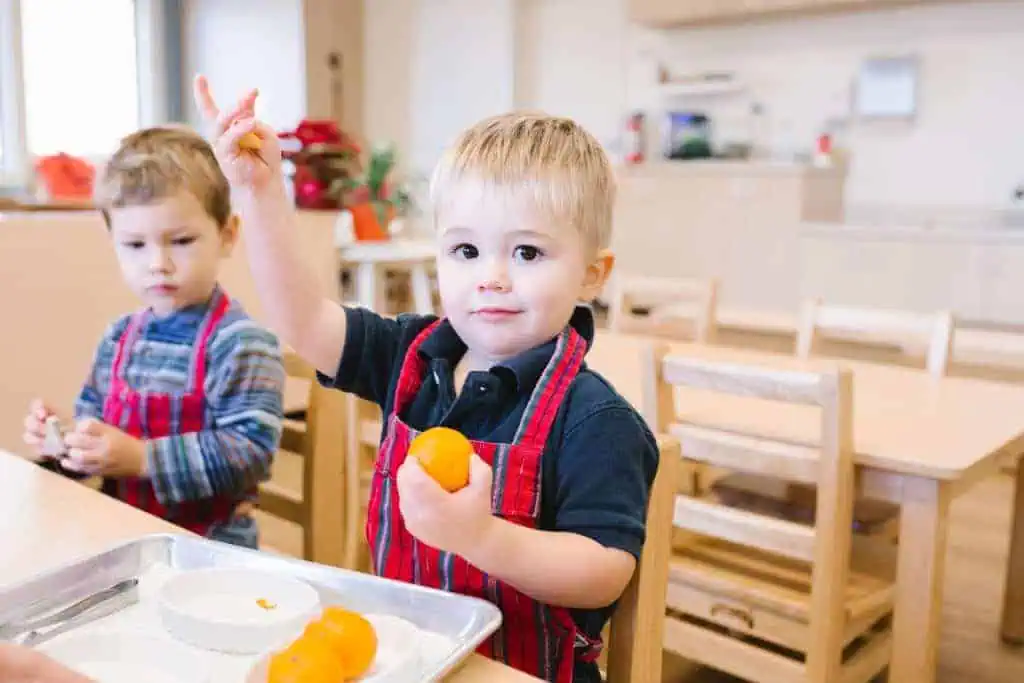 Toddler at Guidepost Montessori practicing independence by peeling an orange during a Practical Life activity.
