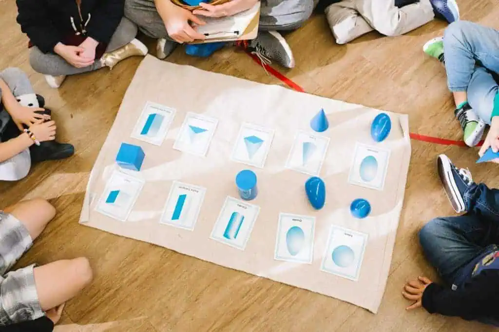 Children at Guidepost Montessori exploring geometric solids and matching cards during a sensorial lesson.