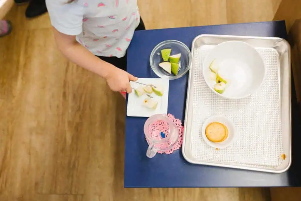 Child at Guidepost Montessori slicing fruit independently as part of a Practical Life lesson.