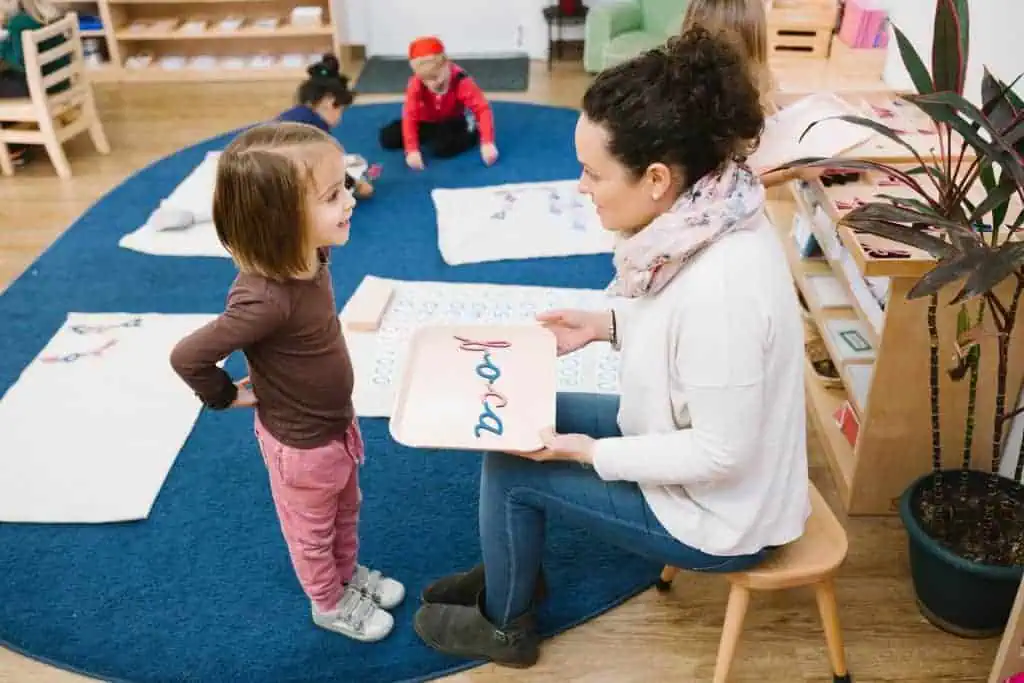 Guide presenting a language lesson to a young child using Montessori letter materials at Guidepost Montessori.