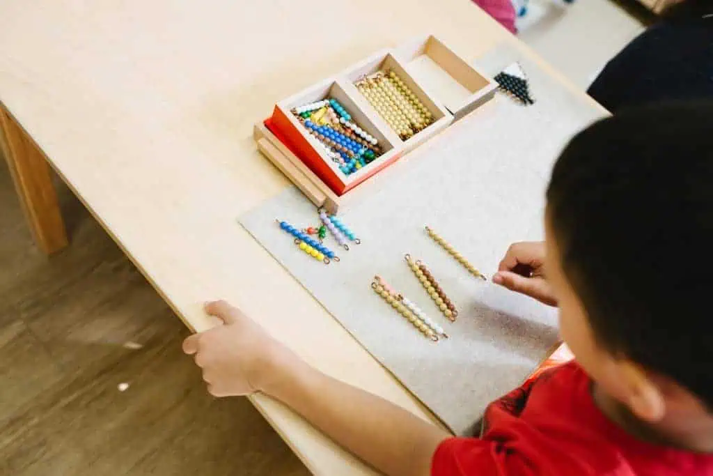 Child arranging Montessori golden bead materials to explore place value at Guidepost Montessori.