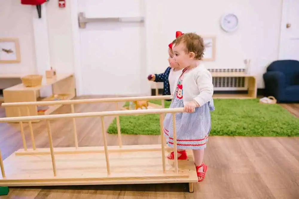 Infant using a Montessori movement bar for self-initiated standing, rather than baby essentials like baby walkers.