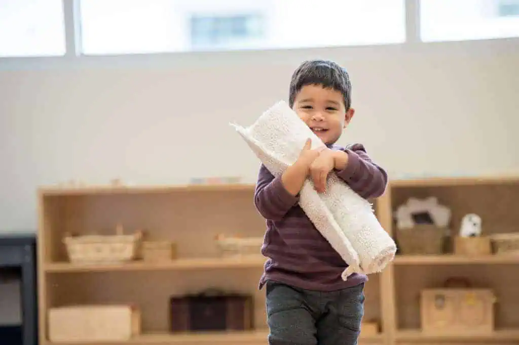parenting advice for preschoolers child carrying rolled mat in Montessori classroom