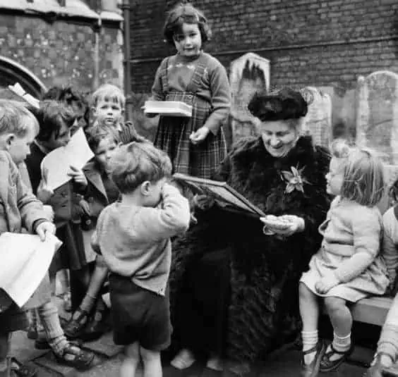 Maria Montessori sitting with young children during a lesson, representing her belief that education can help answer the question is peace possible.