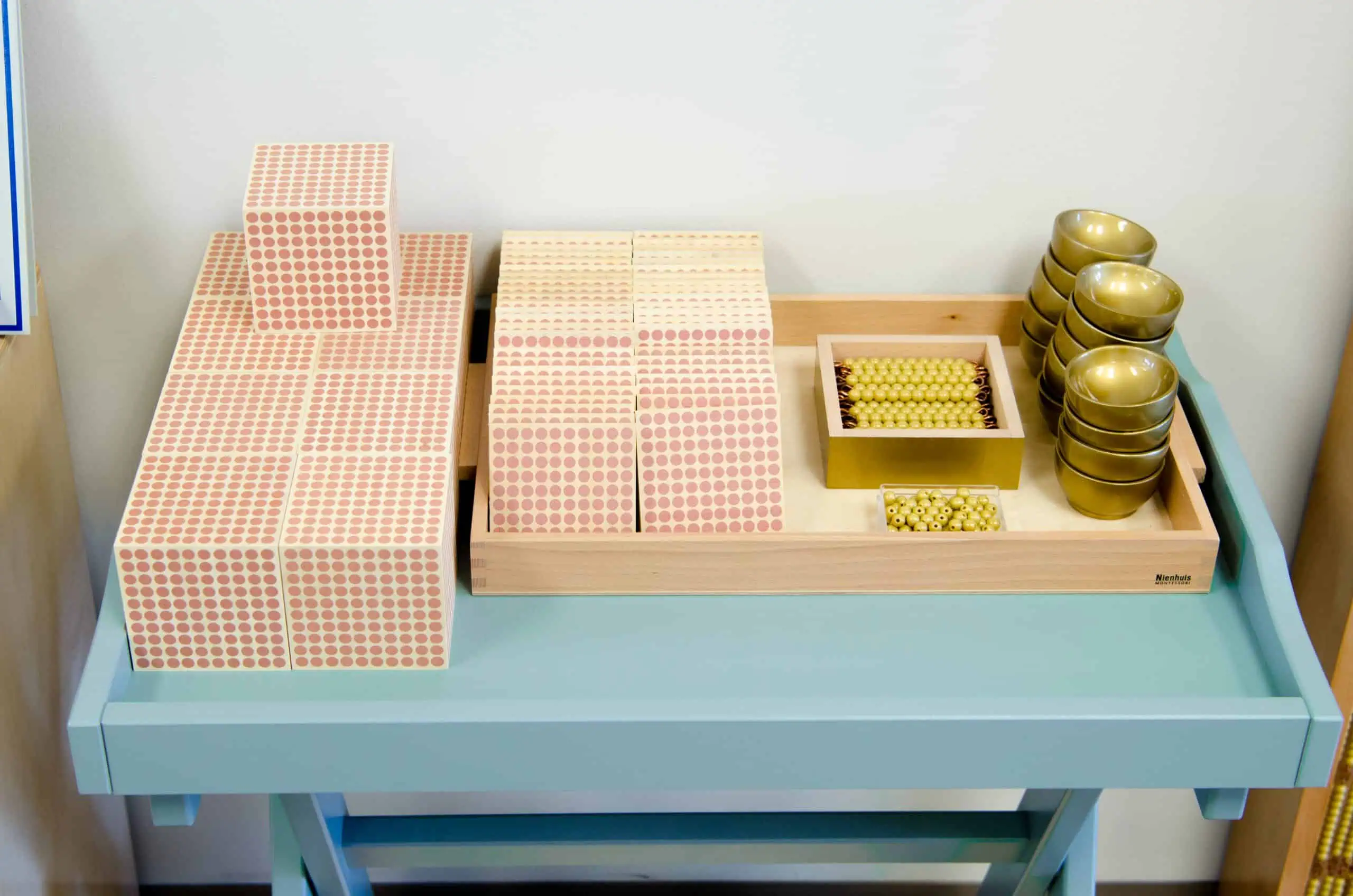 Nienhuis Montessori dot cabinet and golden bead materials on a classroom shelf — what is Montessori math material