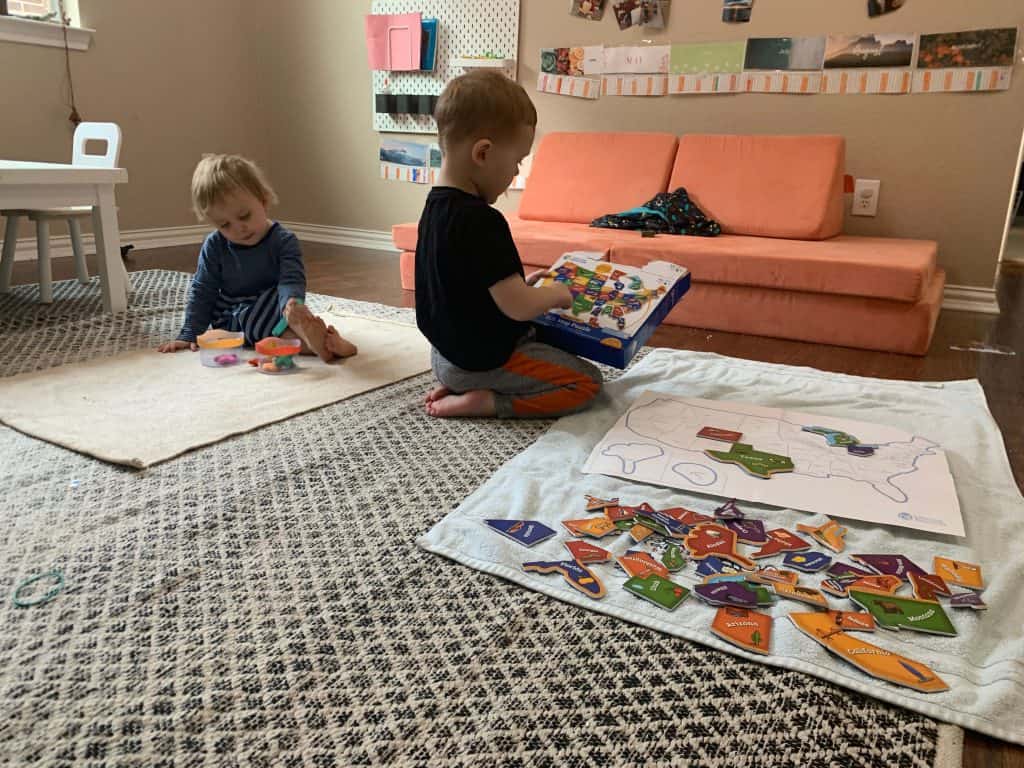 Two children engaging in Montessori activities on a cozy rug.