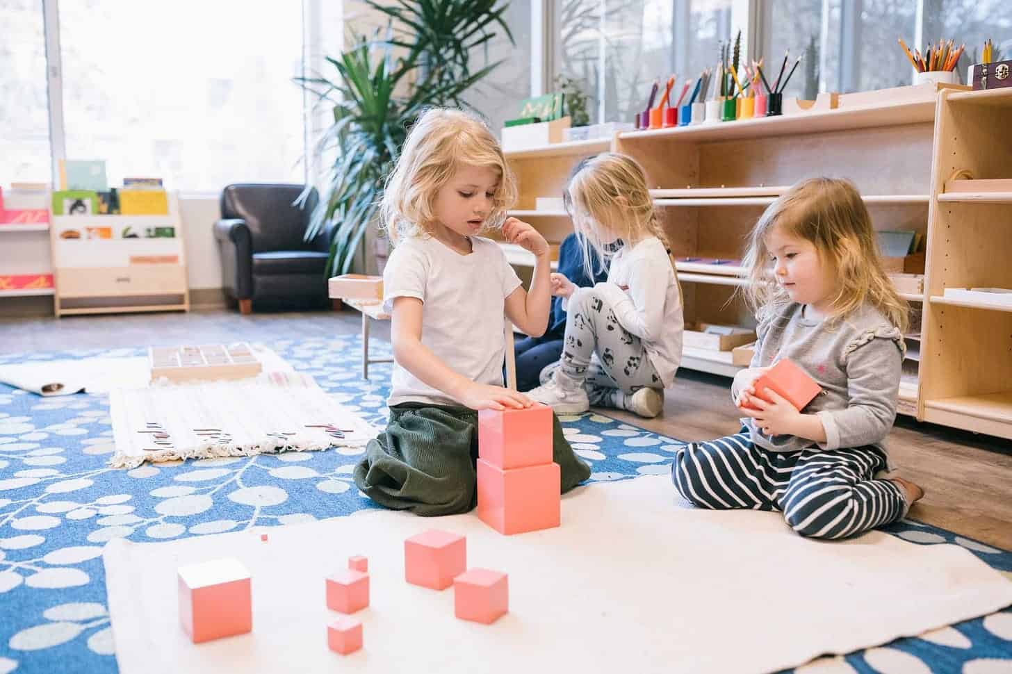 Young children playing with colorful blocks in a Montessori classroom setting.